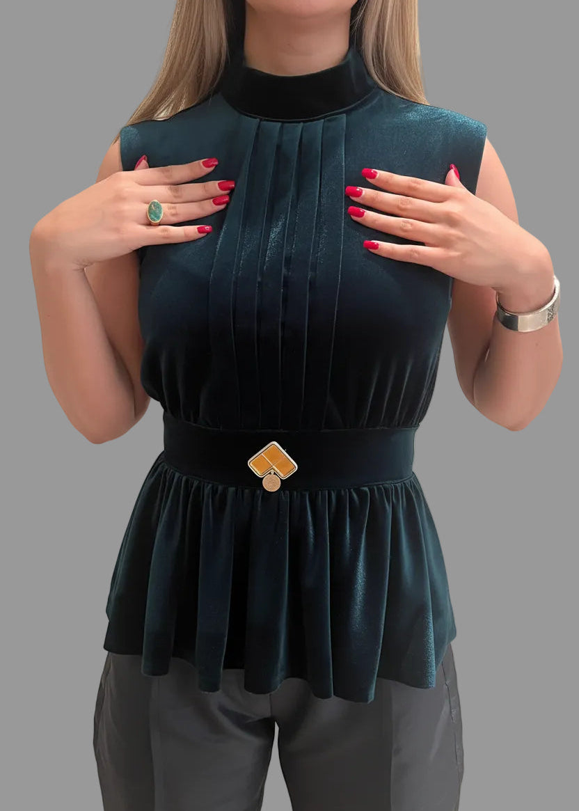 Woman wearing a dark green peplum top with a belt on a gray background