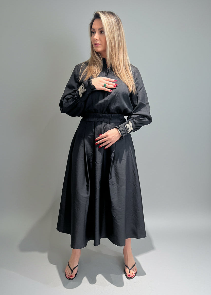 Woman wearing a black dress with long sleeves against a gray background