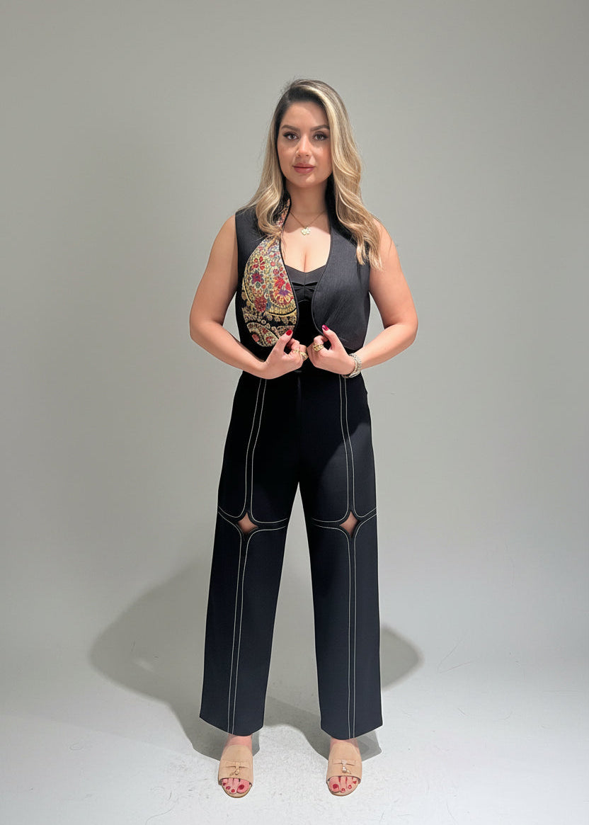Woman wearing a black jumpsuit with floral accents on a gray background