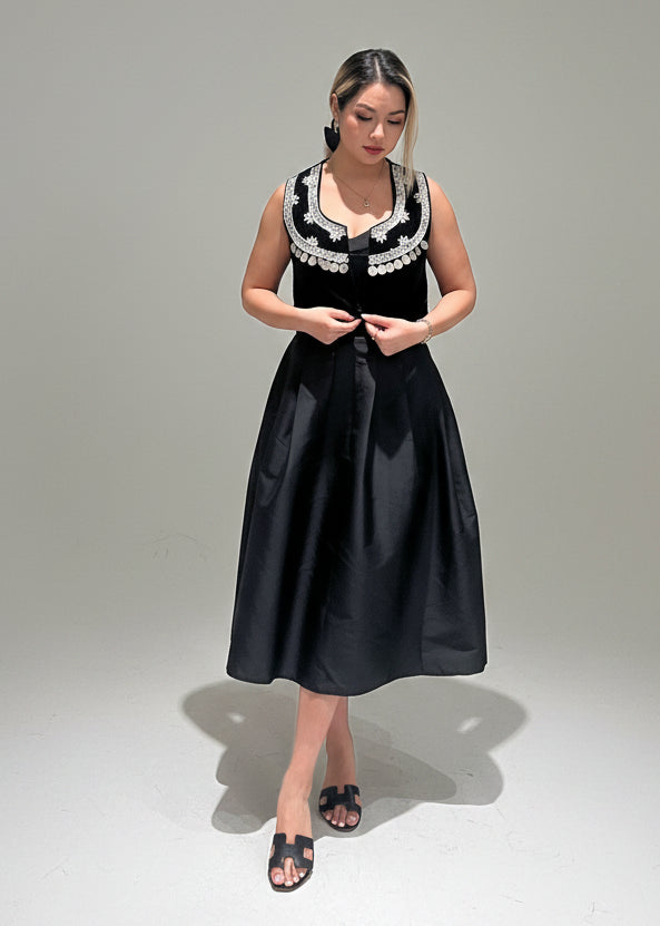 Woman wearing a black dress with white lace details on a gray background