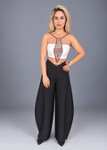 A woman modeling a two-piece outfit consisting of a white strapless crop top with a central embroidered panel and black wide-leg pants, shot against a solid gray studio background.