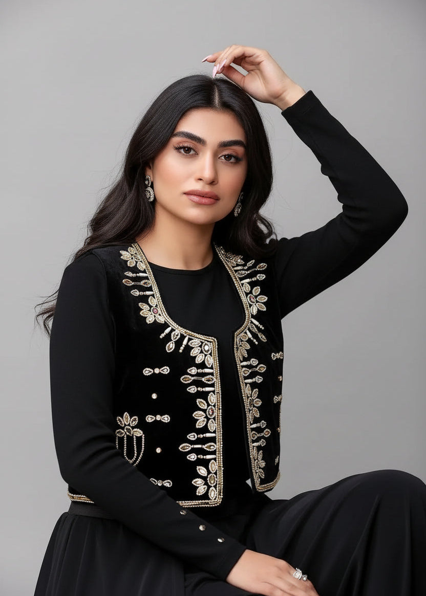 Woman wearing a black outfit with gold embroidery on a gray background
