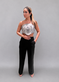 Woman wearing a strapless top and black pants on a gray background