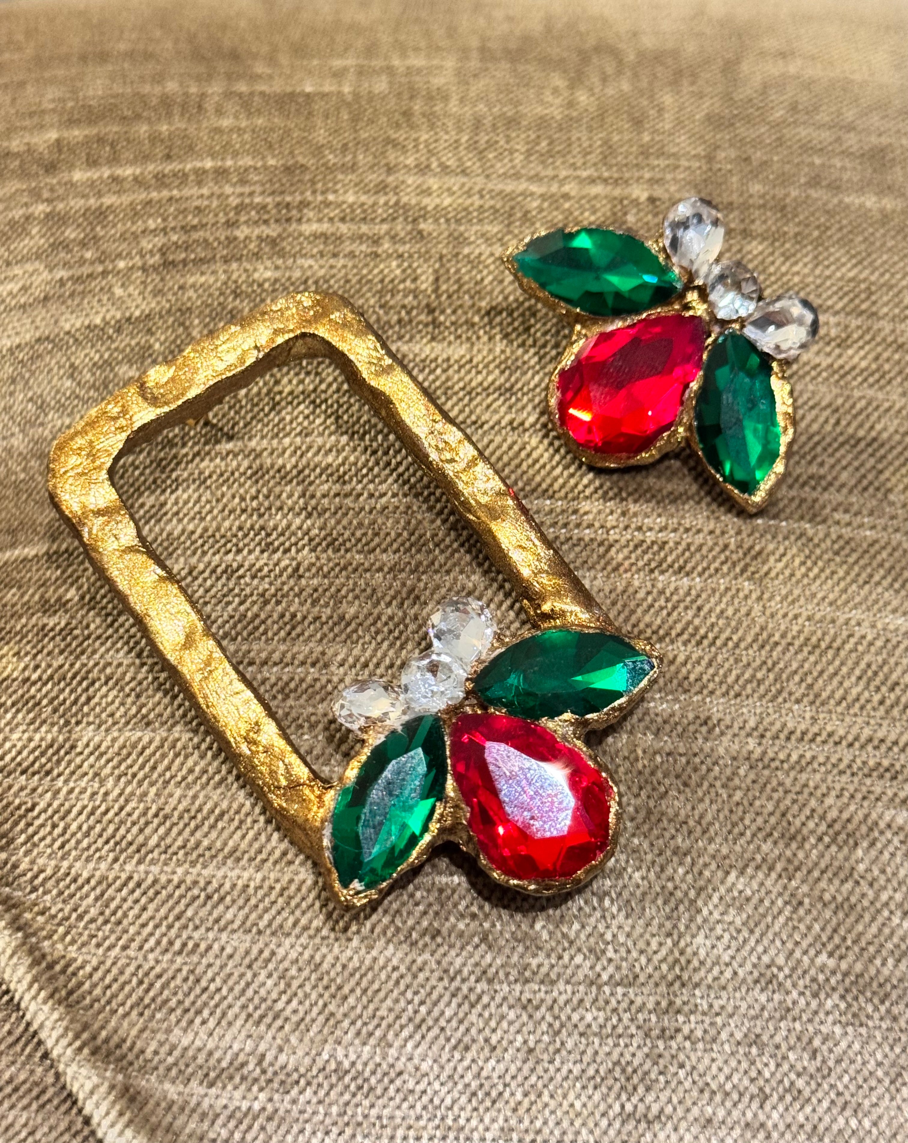 Gold frame with red and green gemstones on a textured beige background
