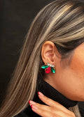 Close-up of a person wearing colorful gemstone earrings against a black background