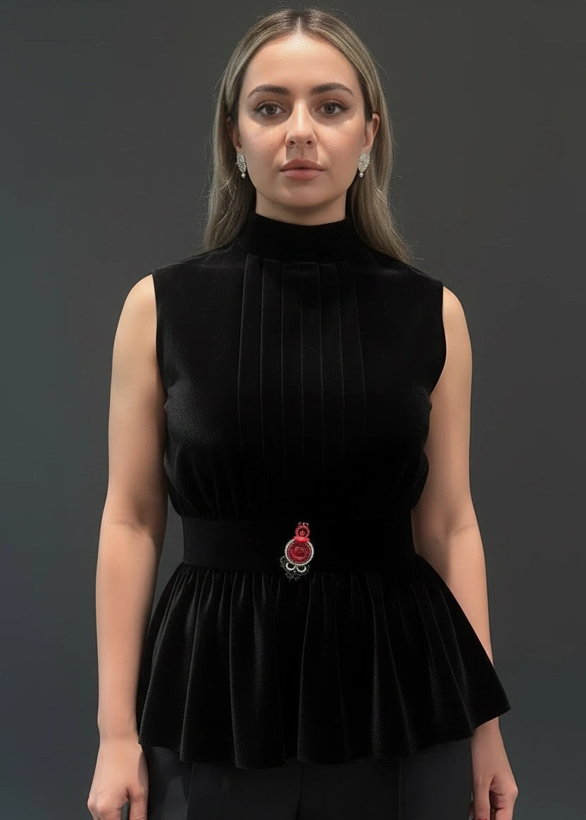 Woman wearing a black velvet top with a brooch on a dark background