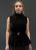 Woman wearing a black velvet top with a brooch on a dark background