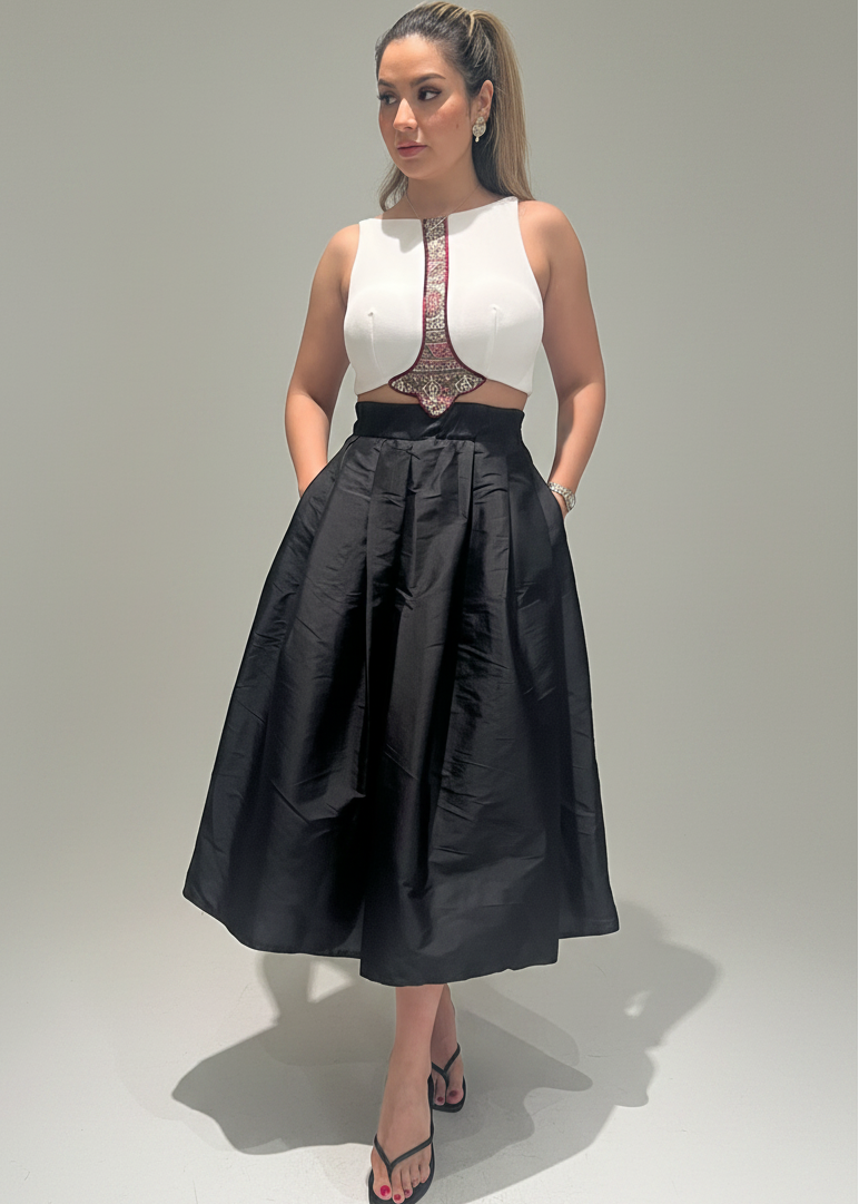 Woman wearing a white top with lace details and a black skirt on a plain background