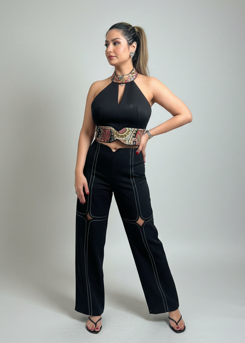 Woman wearing a black outfit with a patterned belt on a gray background