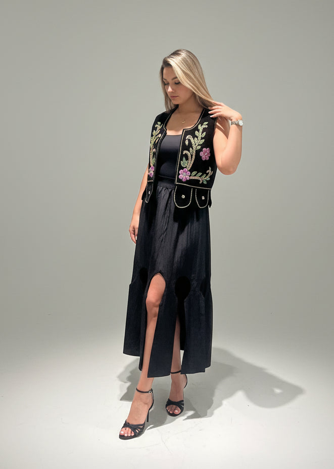 Woman wearing a black dress with floral embroidery on a gray background