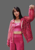 Woman wearing a pink outfit with floral embroidery on a gray background