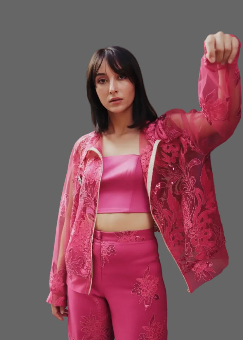 Woman wearing a pink outfit with floral embroidery on a gray background
