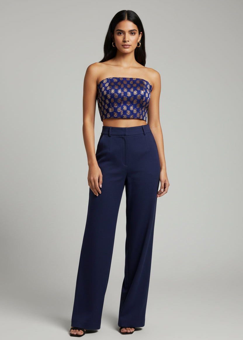 Woman wearing a strapless top and high-waisted pants on a gray background