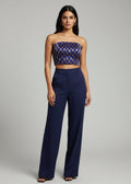 Woman wearing a strapless top and high-waisted pants on a gray background