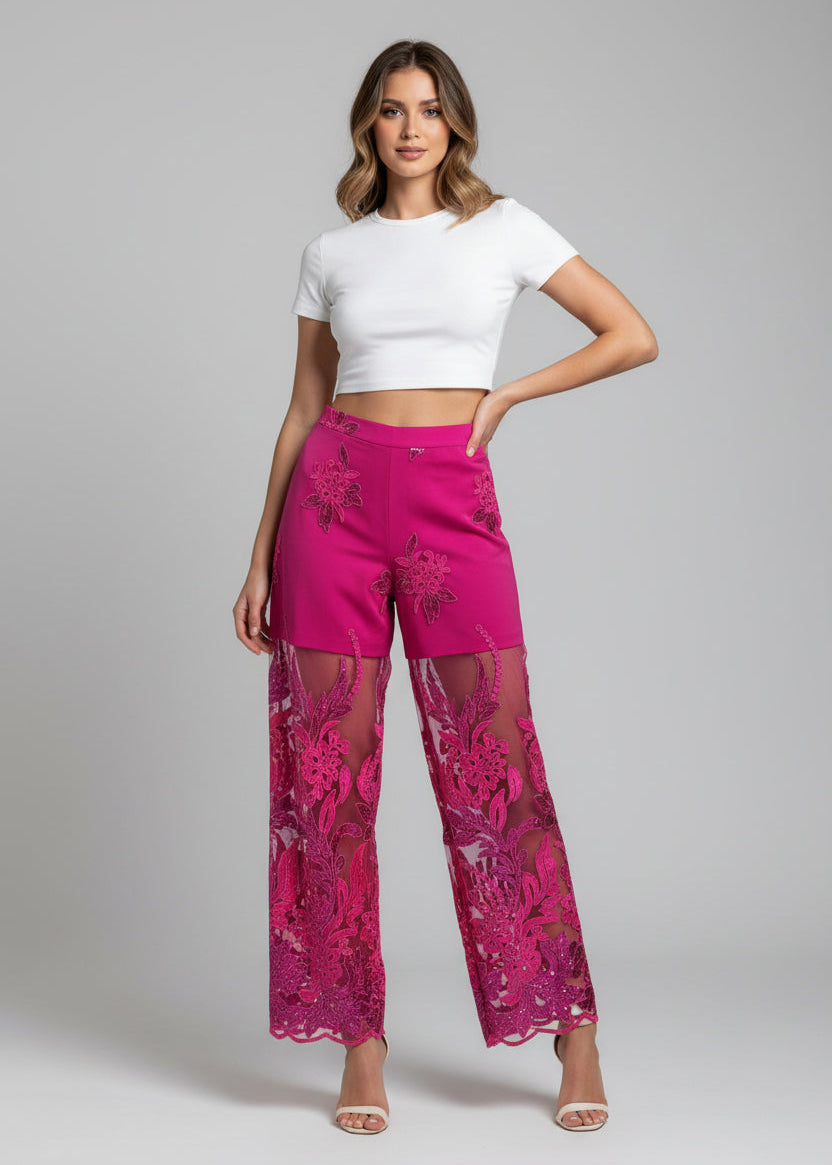 Woman wearing a white crop top and pink lace pants on a gray background