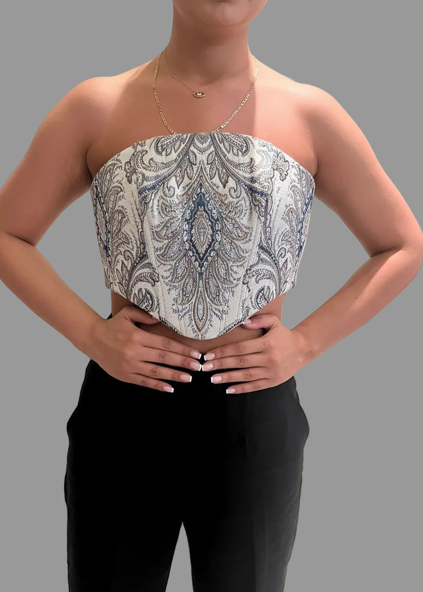 Person wearing a patterned strapless top and black pants on a gray background