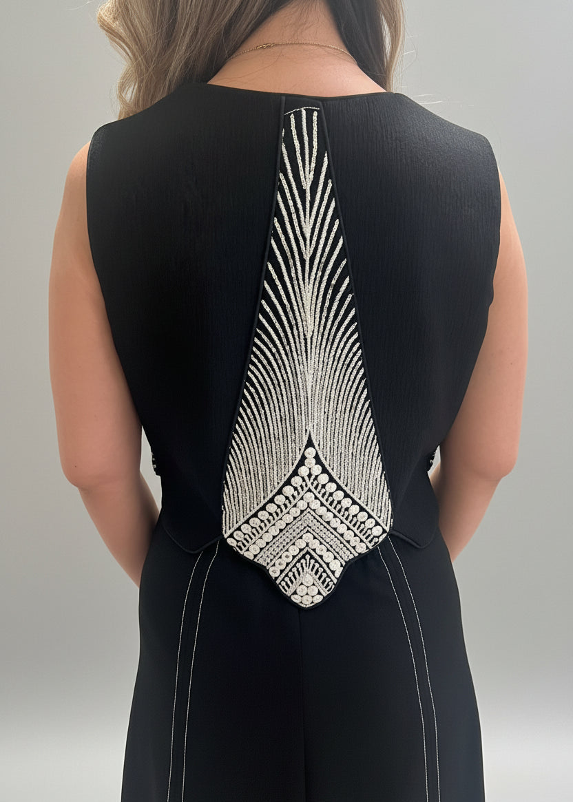 Black dress with intricate white back design on a neutral background