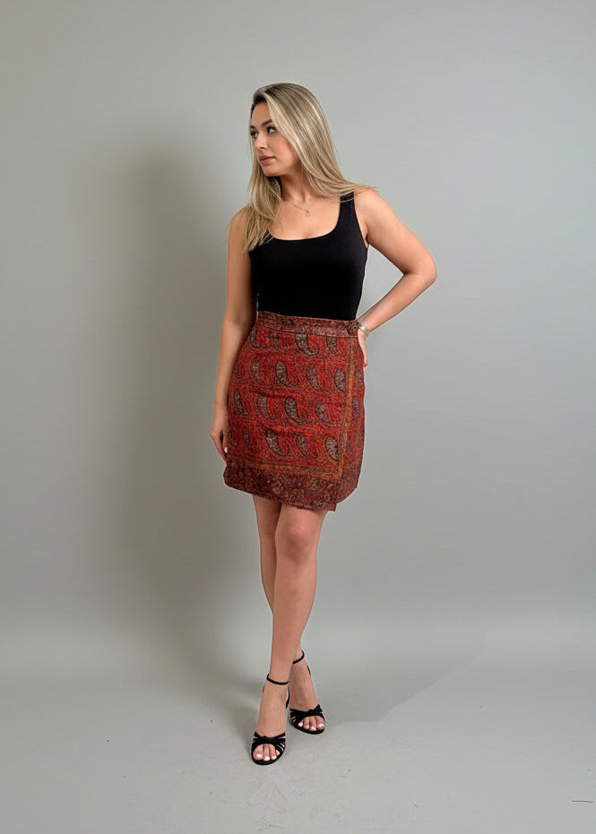Woman wearing a black top and patterned red skirt on a gray background