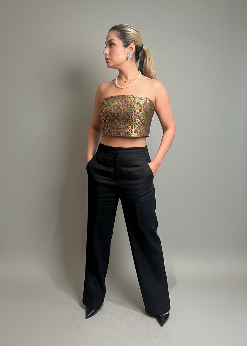 Woman wearing a patterned top and black pants against a plain background
