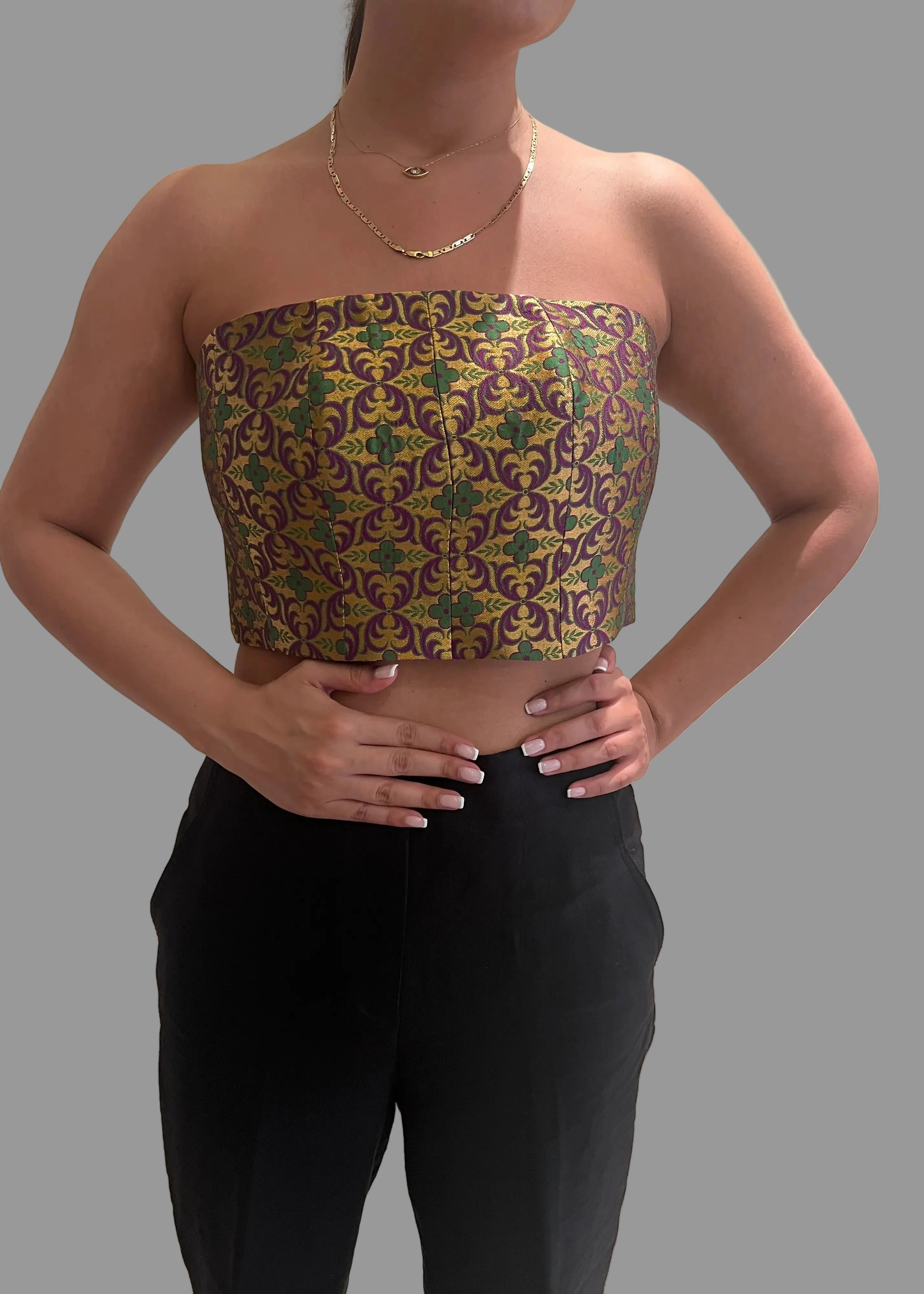 Woman wearing a patterned tube top and black pants on a gray background