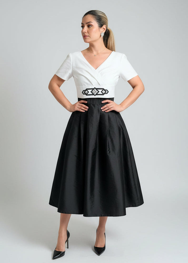 Woman wearing a white top and black skirt with a belt on a gray background