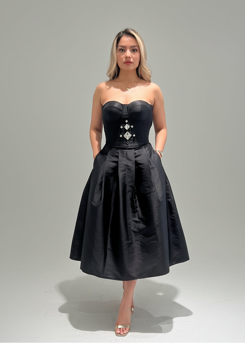 Woman wearing a black strapless dress with decorative elements on a gray background