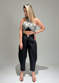 Woman wearing a black and white patterned top and black pants on a gray background