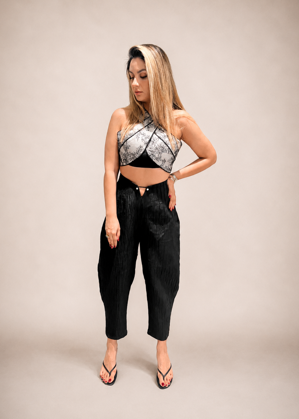 Woman wearing a black and white patterned top and black pants on a gray background
