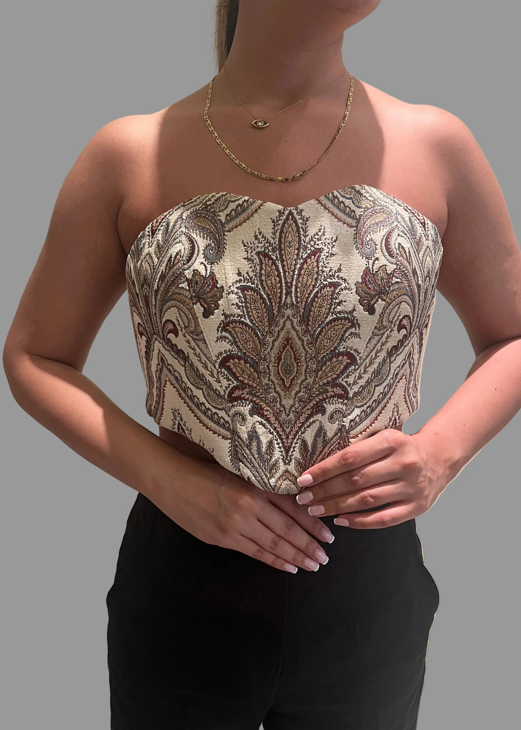 Woman wearing a strapless top with intricate paisley pattern on a plain background