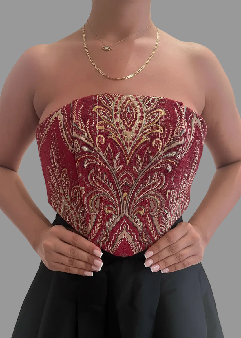 Red strapless top with gold embroidery worn by a person on a gray background
