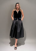 Woman wearing a black sleeveless top and skirt against a plain background