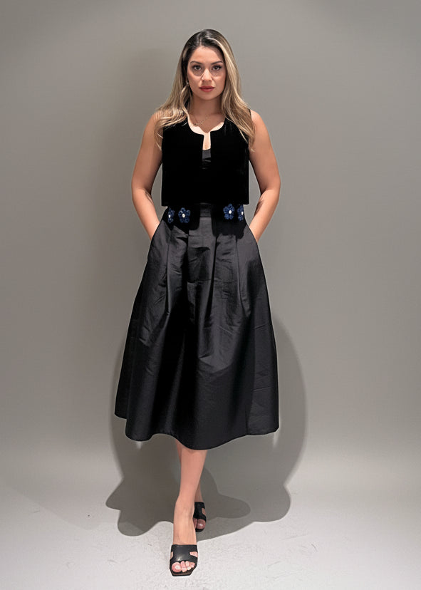 Woman wearing a black sleeveless top and skirt against a plain background