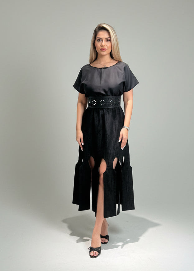 Woman wearing a black dress with cut-out sides on a gray background