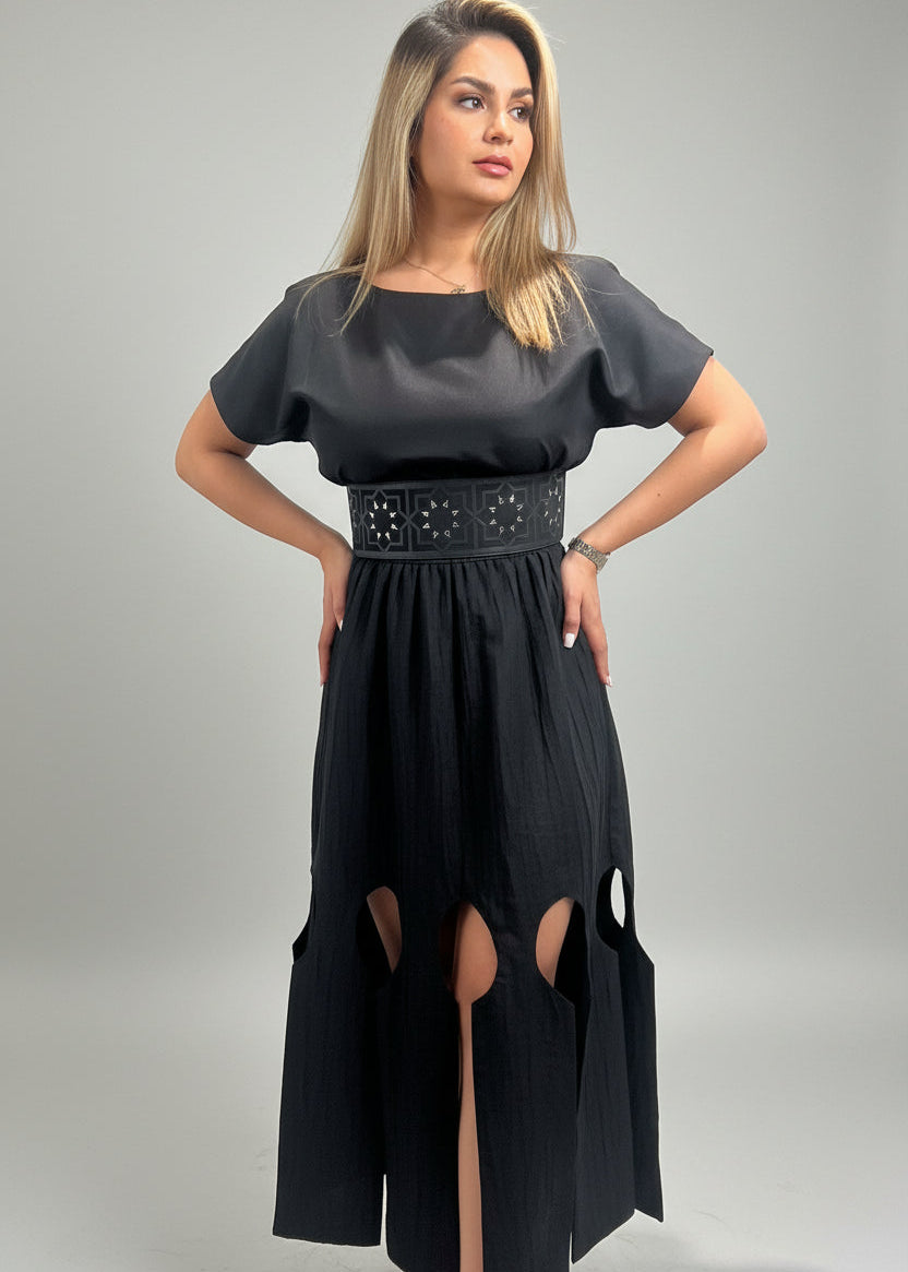 Woman wearing a black dress with cut-out design on a gray background