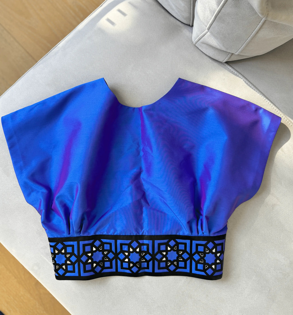 Blue crop top with black lace trim on a white surface