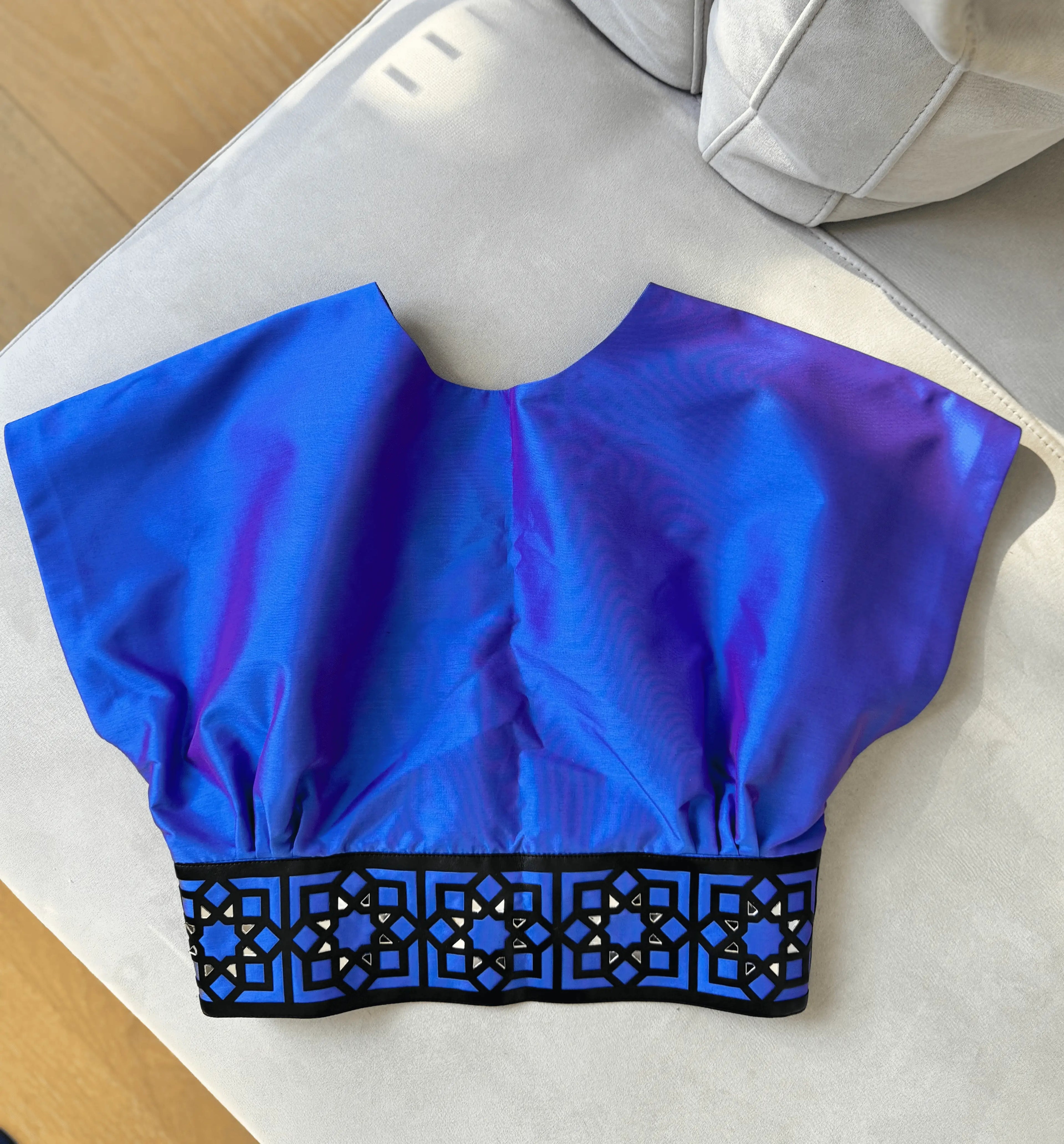 Blue crop top with black lace trim on a white surface