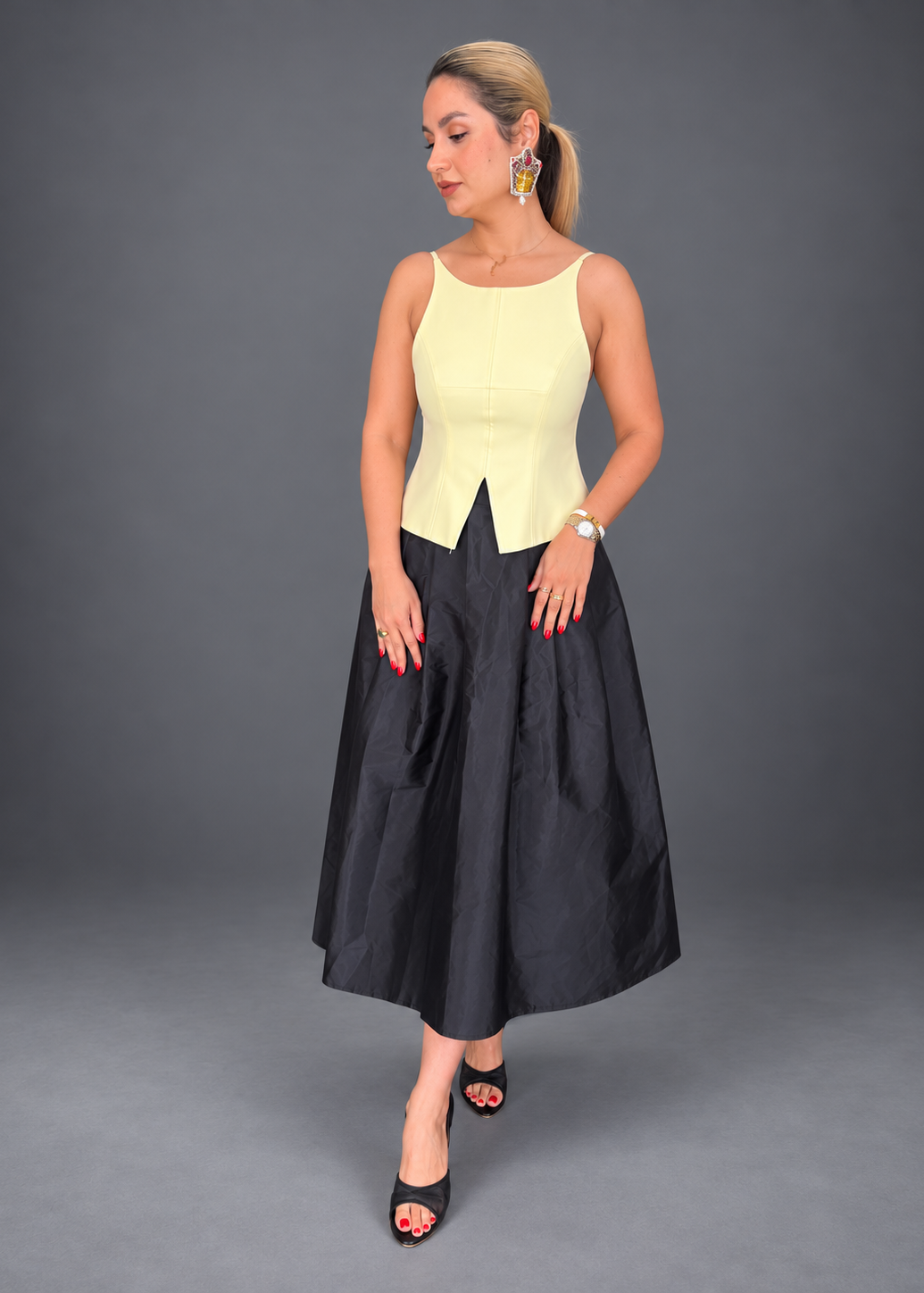 Woman wearing a white top with a black skirt on a gray background