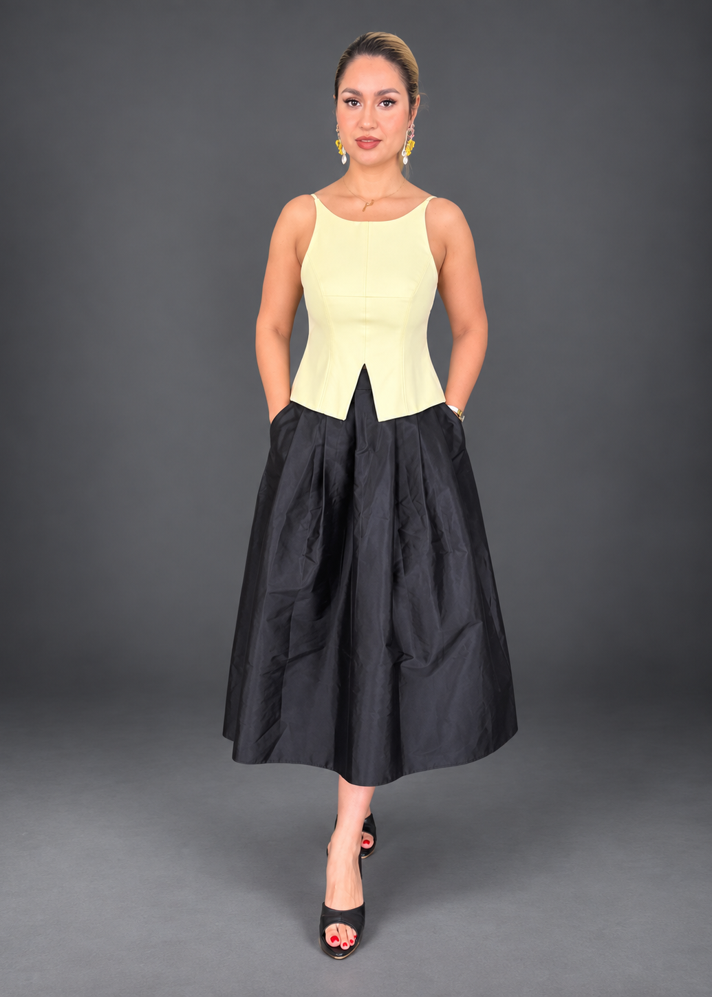 Woman wearing a white top with a black skirt on a gray background
