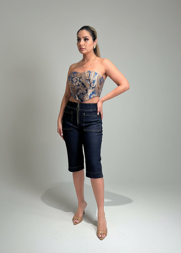 Woman wearing a strapless top with floral pattern and dark jeans on a gray background