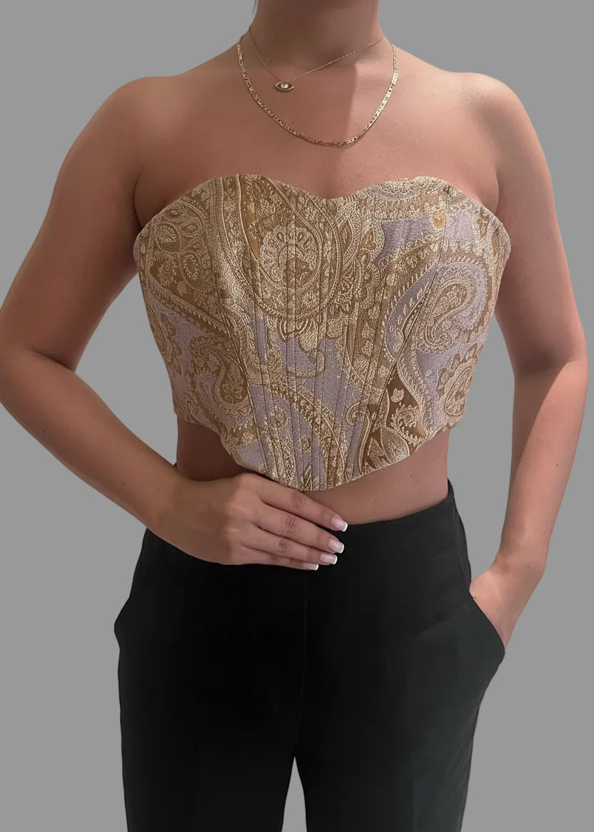 Woman wearing a patterned top and black pants on a gray background