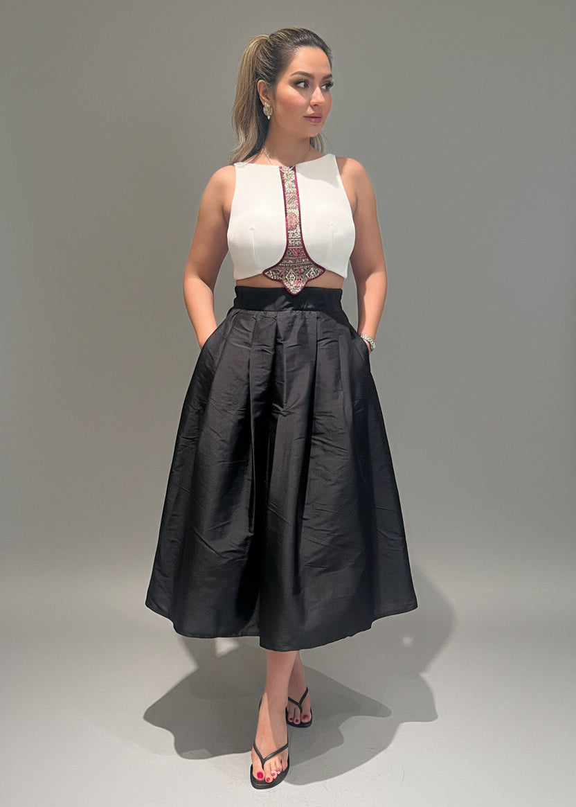 Woman wearing a white top with a black skirt on a gray background