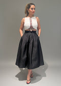 Woman wearing a white top with a black skirt on a gray background