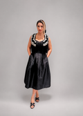 Woman wearing a black dress with white embellishments 
