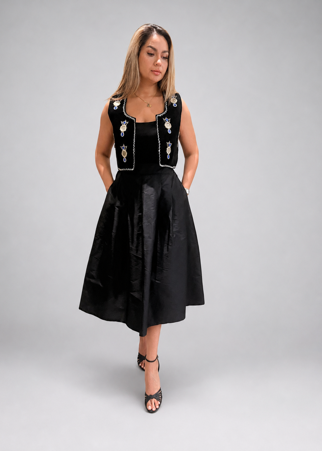 Woman wearing a black dress with an embroidered vest